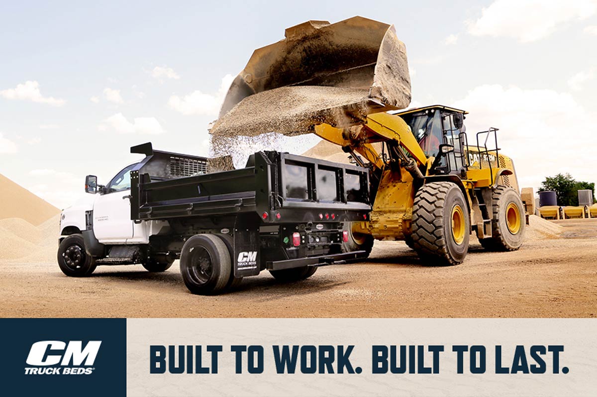 CM Truck Beds Built to Work. Built to Last. Dump bed has gravel poured into the back of the truck bed on job site.